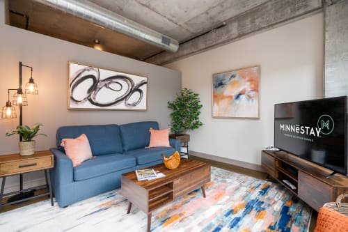 Relax in your stylish living room featuring exposed concrete ceilings, modern art, and warm industrial charm.