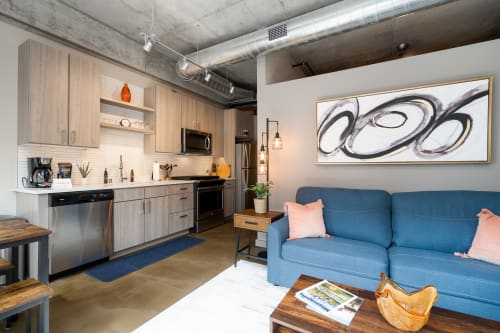 Relax in your stylish loft with exposed ceilings, modern kitchen, and vibrant blue sofa—perfect for unwinding after exploring the city.