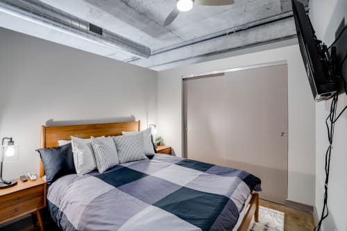 Unwind in your stylish bedroom featuring exposed concrete ceilings and modern industrial charm. The plush bedding promises restful nights in this contemporary urban retreat.