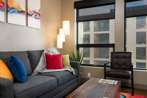 Your stylish living room features a comfy gray sofa with vibrant pillows and contemporary furnishings overlooking the city.