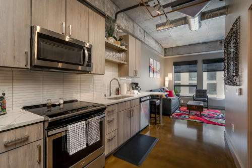 Your modern loft features a sleek kitchen with stainless appliances, flowing seamlessly into your cozy living space with industrial charm.