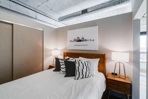 Drift off in this stylish bedroom featuring crisp linens, modern furnishings, and a stunning Minneapolis cityscape print above your plush bed.