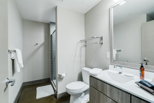Step into your modern ensuite with pristine white vanity, walk-in shower, and fresh towels waiting for your arrival.