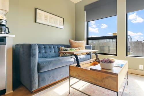 Sink into your plush velvet sofa while natural light streams through oversized windows, creating the perfect spot to unwind with coffee and city views.