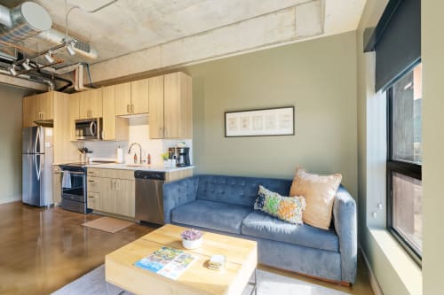 Sink into the plush blue sofa in your open-concept space, where modern industrial charm meets cozy comfort.