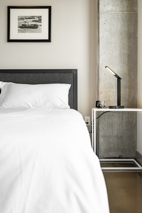 Sink into crisp white linens in your modern bedroom, where industrial concrete meets sleek design for a peaceful night's rest.