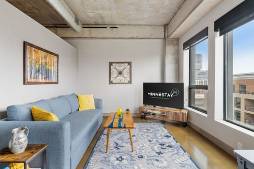 Sink into your comfortable sectional sofa while enjoying city views and entertainment in this bright, modern living space with exposed concrete details.