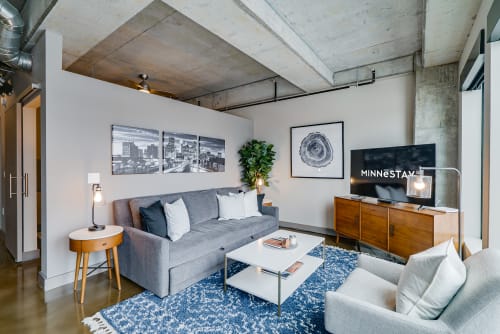 Relax in your sleek living space with exposed concrete ceilings, plush seating, and modern entertainment setup.