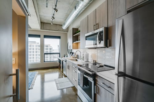 Your modern kitchen combines sleek stainless steel appliances with warm wood cabinets, perfect for creating memorable meals while city views unfold beyond.