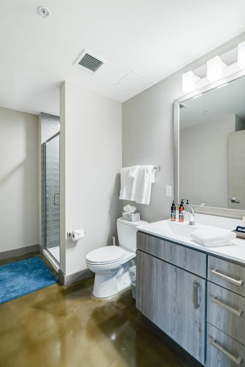 Step into your sleek modern bathroom featuring a spacious shower, polished floors, and premium amenities for your comfort.