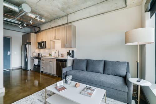 Relax in your stylish open-concept space with exposed concrete ceilings and modern finishes for an urban loft experience.