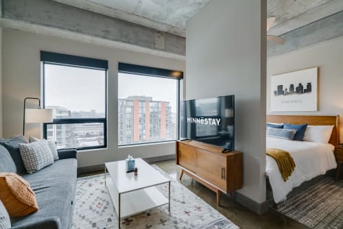 Relax in your modern loft with exposed concrete beams, city views through floor-to-ceiling windows, and cozy living space.