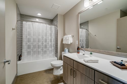 Refresh in your modern bathroom with gray tile accents, spacious vanity, and relaxing tub-shower combo.