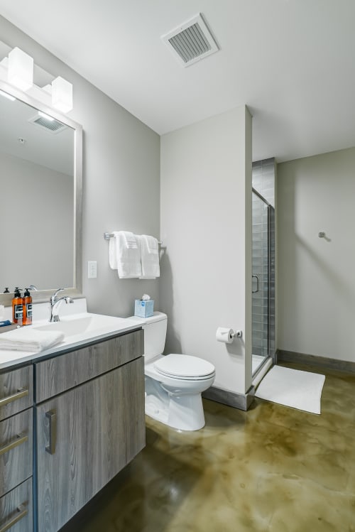 Step into your sleek modern bathroom featuring polished concrete floors, a spacious walk-in shower, and thoughtful amenities for your comfort.