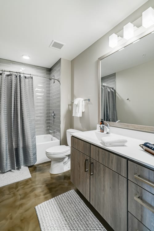 Your modern bathroom features sleek gray finishes, a spacious tub-shower combo, and warm wood vanity for comfortable daily routines.