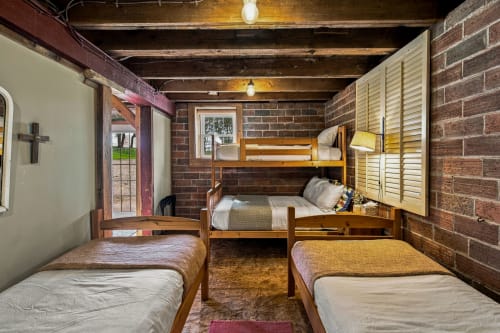Your rustic bunk room blends exposed brick and warm wood beams, creating a charming retreat where everyone can unwind together after a day of adventure.