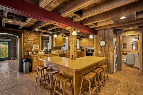 Step into your open-concept kitchen where rustic wooden beams and warm lighting create a cozy mountain retreat. Gather around the spacious island with seating for your group, fully equipped for home-cooked meals and memorable evenings together.