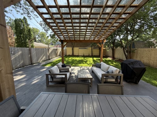 Unwind on your private deck with comfortable seating and BBQ, surrounded by lush greenery and dappled sunlight through the pergola.