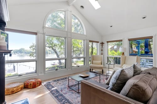 Relax in your bright living room where floor-to-ceiling windows frame stunning lake views, creating a serene retreat.
