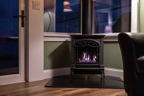 Cozy up by your crackling fireplace while watching the night sky through floor-to-ceiling windows in this warm, inviting living space.
