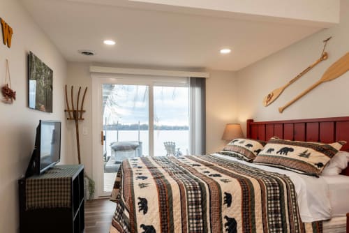 Wake up to stunning lake views through your bedroom's sliding doors, where cozy cabin charm meets waterfront luxury.