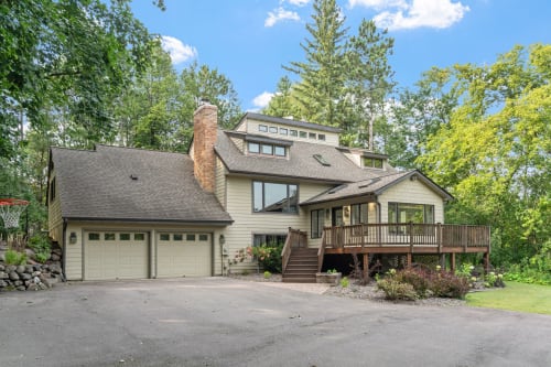A stunning multi-level vacation home nestled among mature trees, featuring a spacious deck and two-car garage in a peaceful wooded setting.