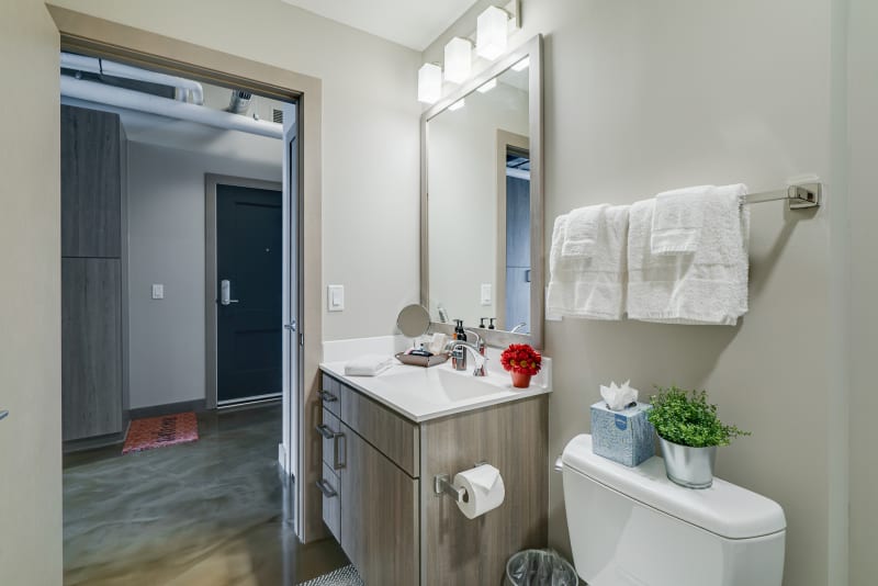 Step into your modern bathroom with pristine white countertops, warm wood vanity, and plush towels awaiting your arrival.