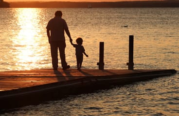 Man and child on a pier at sunset.