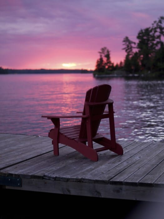 Deck chair on a lake pier at sunset.