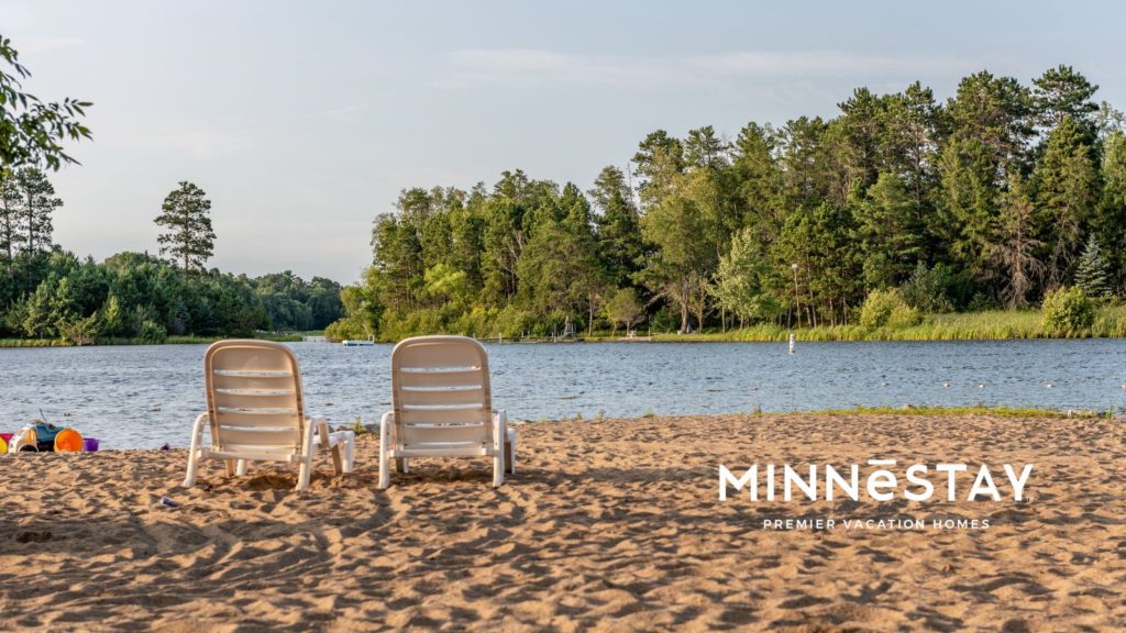 Two white chairs in the sandy beach of a Minneasota lake