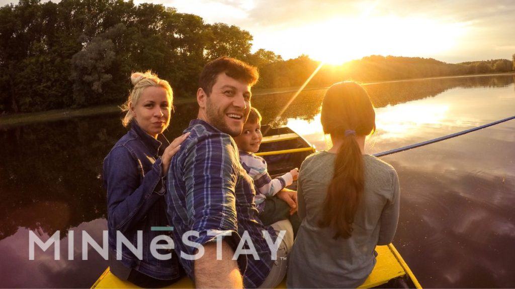 Family enjoying their Family vacation in a MINNeSTAY vacation rental sitting on a dock at sunset.